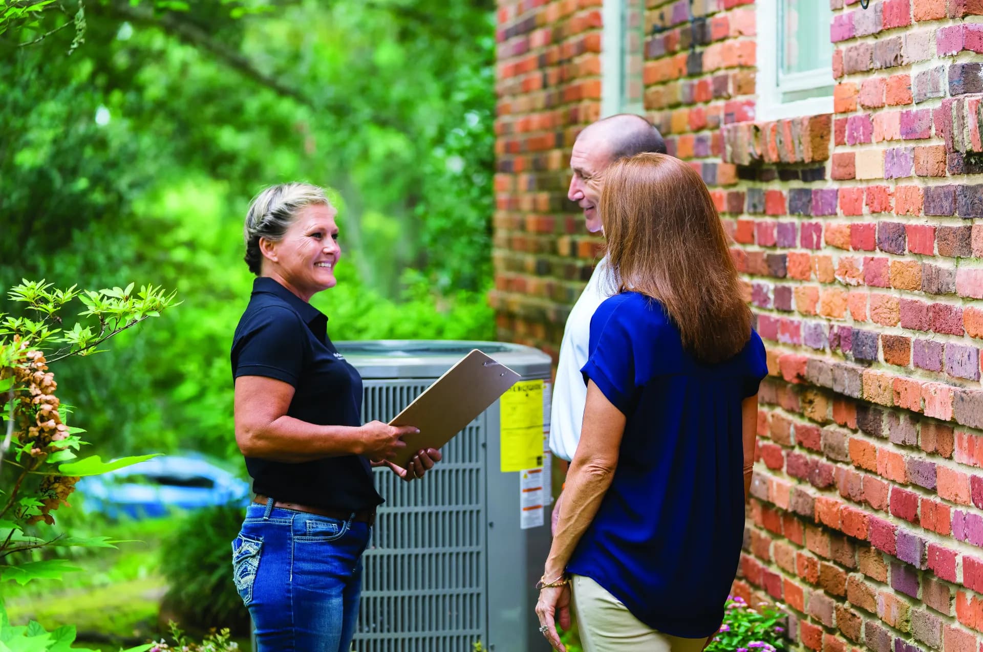 Myers technician consulting with homeowners next to an outdoor HVAC unit